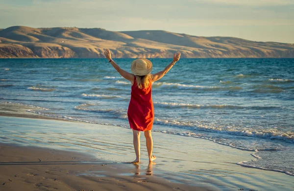 快乐迷人的成熟女人 穿着红色衣服 在户外尽情享受 在海滩上自由自在 张开双臂 伸展着蓝色的大海和美丽的风景 退休生活方式和福利概念 — 图库照片