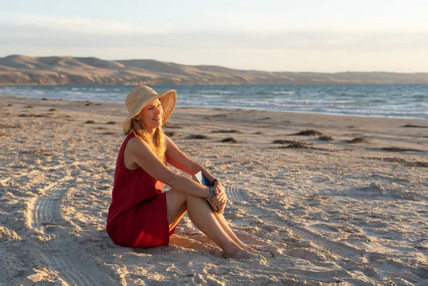 穿着红色衣服的成熟女人快乐而迷人 在空旷的海滩上看书和放松 享受户外生活和自由 退休生活方式 希望和精神健康概念 — 图库照片
