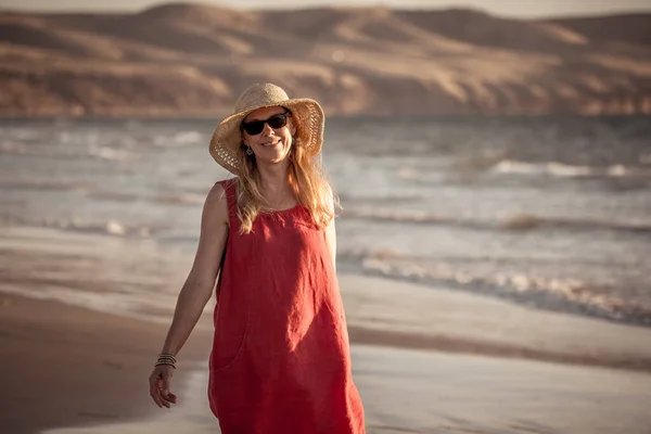 穿着红色衣服的迷人的成熟女人喜欢户外散步 喜欢在沙滩上自由自在地散步 拥有蓝色的大海和美丽的风景 希望和福祉概念 — 图库照片