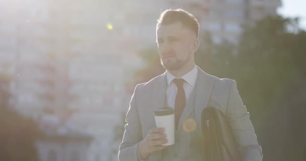 Seriöser Anwalt trinkt Kaffee im Hintergrund im Park. — Stockvideo