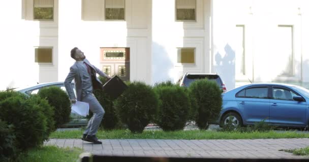 A rich businessman with a briefcase throws white sheets of paper in the city. — Stock Video