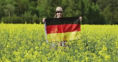 Sarı kolza tohumu tarlasında Alman bayrağı taşıyan çekici bir kadın..