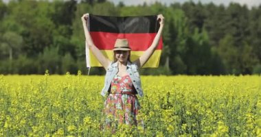 Sarı kolza tohumu tarlasında Alman bayrağı taşıyan yetişkin bir kadın.