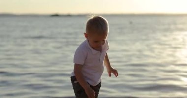 Gün batımında gölün kıyısında tatlı bir çocuk yürüyor..