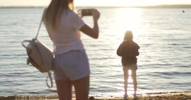 Annem gün batımının arka planında kızının fotoğraflarını çekiyor.