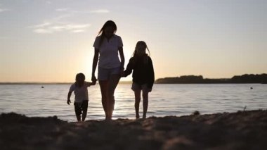 Mutlu aile gün batımında gölün kenarında yürüyor..