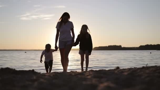 Щасливі сімейні прогулянки біля озера на фоні заходу сонця . — стокове відео
