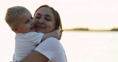 Anne ve küçük oğlu güzel bir günbatımının arka planında sarılıyorlar..