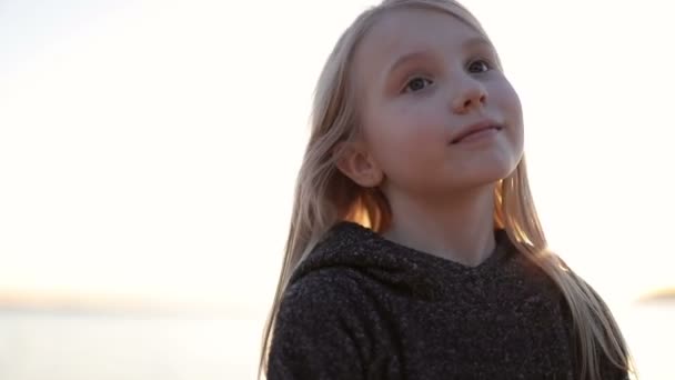 Cara de cerca de la linda chica rubia sobre un fondo de una hermosa puesta de sol . — Vídeos de Stock