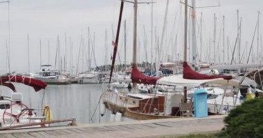Birçok yelkenli ve yat limandaki rıhtımda duruyor..