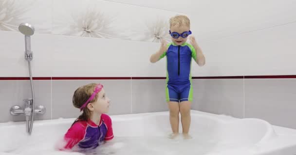 Kleine jongen met blauwe zwembril springt in het water in een bad. — Stockvideo