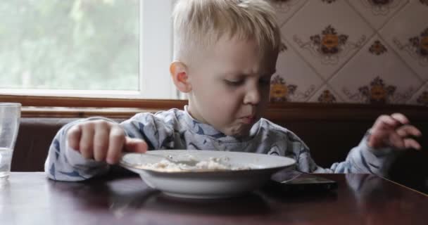 Porträt eines kleinen Jungen, der Haferbrei isst. — Stockvideo