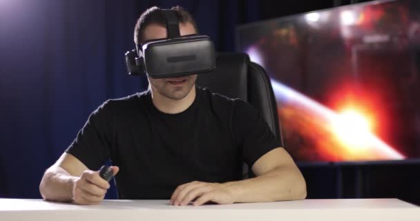 Virtual reality. The man looks through the VR glasses with headphones using remote controller. — Stock Video