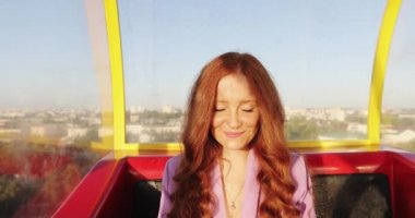 Kıvırcık kızıl saçlı kızın portresi füniküler ya da dönme dolaptan günbatımının tadını çıkarıyor..