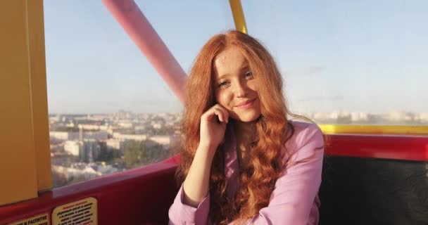 Portrait of sun kissed girl enjoying ity sunset from a window of funicular or ferris wheel cabine. — Stock Video
