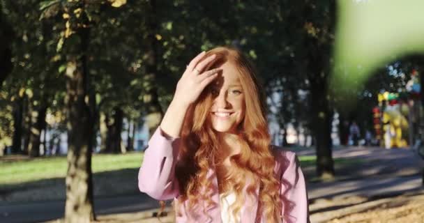 Πορτρέτο του νεαρού θηλυκό μοντέλο με φυσικές φακίδες προσαρμογή των μαλλιών στο έντονο φως του ήλιου. — Αρχείο Βίντεο