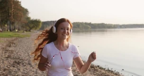 Joven mujer sonriente con el pelo rizado rojo haciendo ejercicios deportivos por la noche . — Vídeos de Stock