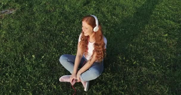 Young happy woman with red curly hair enjoying music. — Stock Video