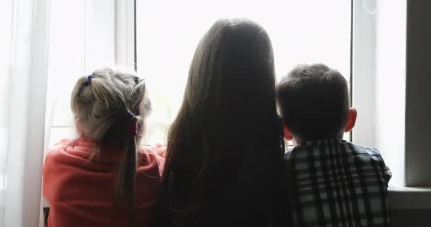 Tres niños miran por la ventana durante Covid-19 . — Vídeos de Stock
