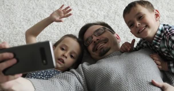 Rodina leží na podlaze a dělá selfie. — Stock video