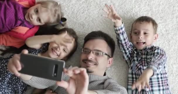 特写父亲和孩子们躺在地板上，给亲戚们打视频电话. — 图库视频影像
