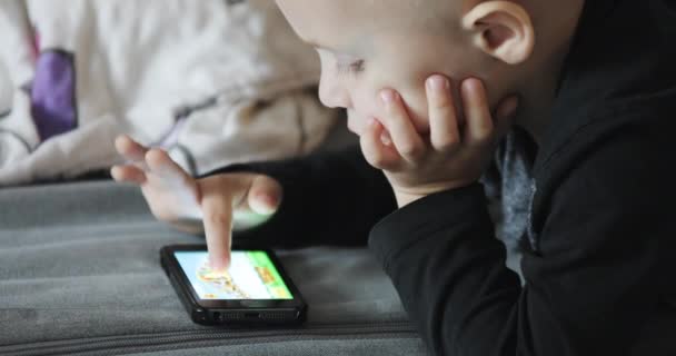 Cute baby kłamie i gra w telefon komórkowy w domu. — Wideo stockowe