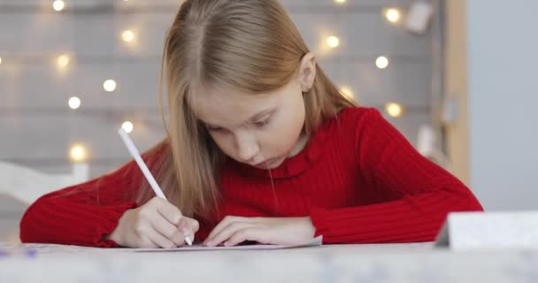 Porträt eines süßen kleinen Mädchens mit blonden Haaren, das einen Brief an den Weihnachtsmann schreibt. — Stockvideo