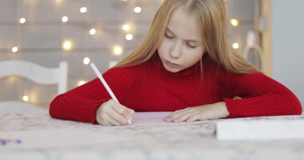 Aranyos lány levelet ír az asztalhoz.. — Stock videók
