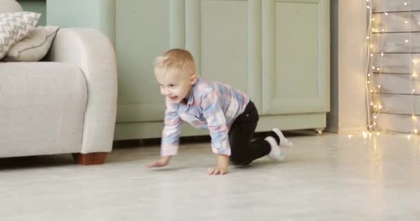 Веселый мальчик ползает на коленях по полу. — стоковое видео