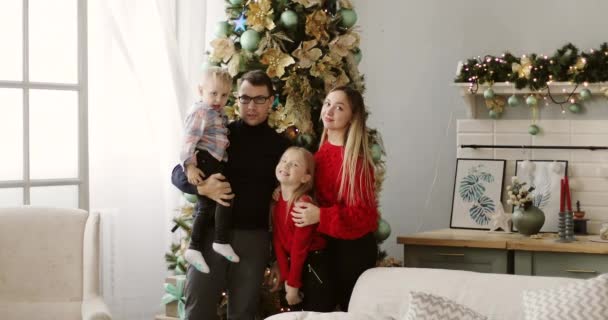 Hermosa familia sonriendo cerca del árbol de Navidad. — Vídeo de stock