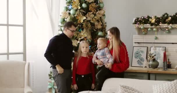 Een gelukkig gezin staat naast de kerstboom. — Stockvideo