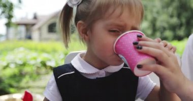 Annem küçük bir kızın bardaktan su içmesine yardım eder..