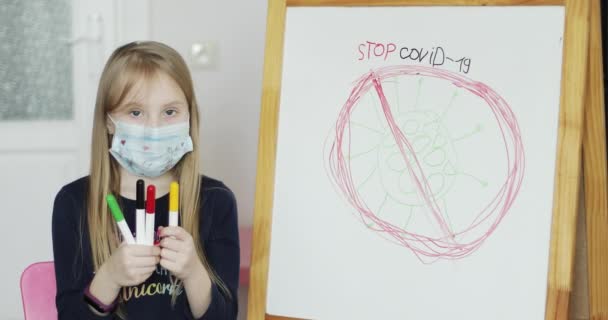 En skolepige i en beskyttende medicinsk maske trak et stop virus covid 19. – Stock-video