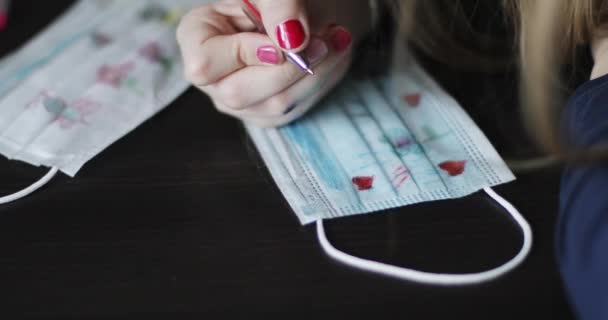 Primo piano di mano ragazze disegnare cuore rosso sulla maschera medica. — Video Stock