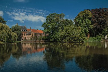 Bruges'te yeşillikler ve eski tuğla binaile çevrili göl