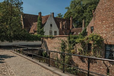 Bruges kanalında eski tuğla evler ve yeşillikler