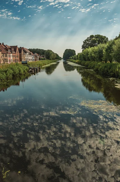 Huizen en grove langs kanaal met hemel weerspiegeld op water in Damme — Stockfoto