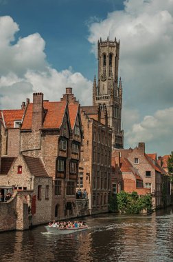 Bruges kanalı üzerinde tuğla binalar ile tekneler ve yapraklı ağaç