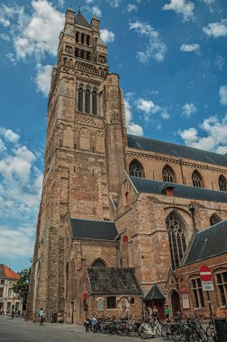 Bruges bir sokakta insanlar ve bisiklet ile Kilise kulesi