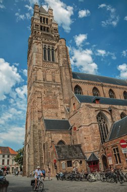 Bruges bir sokakta insanlar ve bisiklet ile Kilise kulesi