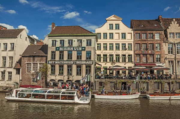 Старые здания перед каналом с лодками и людьми в Генте — стоковое фото