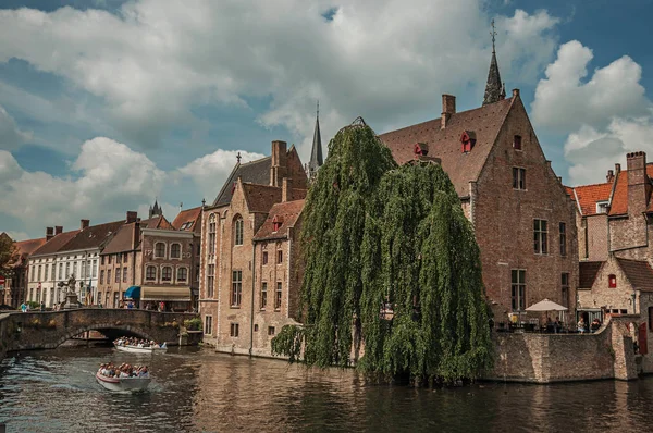 A Bruges-i csatornán lévő tégla épületekkel rendelkező hajók és lombos fa — Stock Fotó