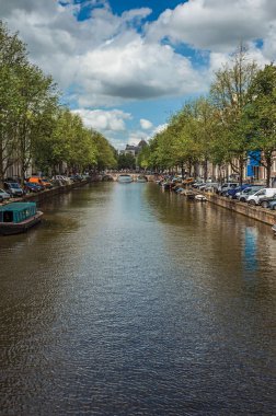 Amsterdam'da eski tuğla binalar ve demirli tekneler ile Kanal