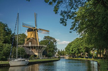 Weesp'te teknelerle kanalın yanında ev ve ahşap sarı yel değirmeni