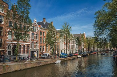 Amsterdam'da eski tuğla binalar ve demirli tekneler ile Kanal