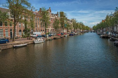 Amsterdam'da eski tuğla binalar ve demirli tekneler ile Kanal