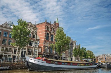 Amsterdam'da tuğla binalar ile kanal tarafında demirlemiş büyük tekne