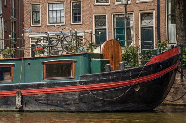 Amsterdam'da kanal tarafında ve eski binalarda demirlemiş büyük tekneler