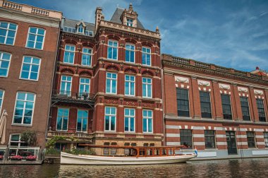 Amsterdam'da kanal tarafında ve tuğla binalarda demirlemiş tekne