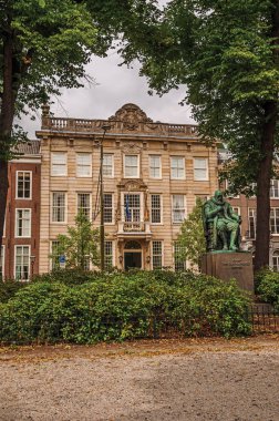 Lahey'deki tuğla binaların önünde bahçede bronz heykel